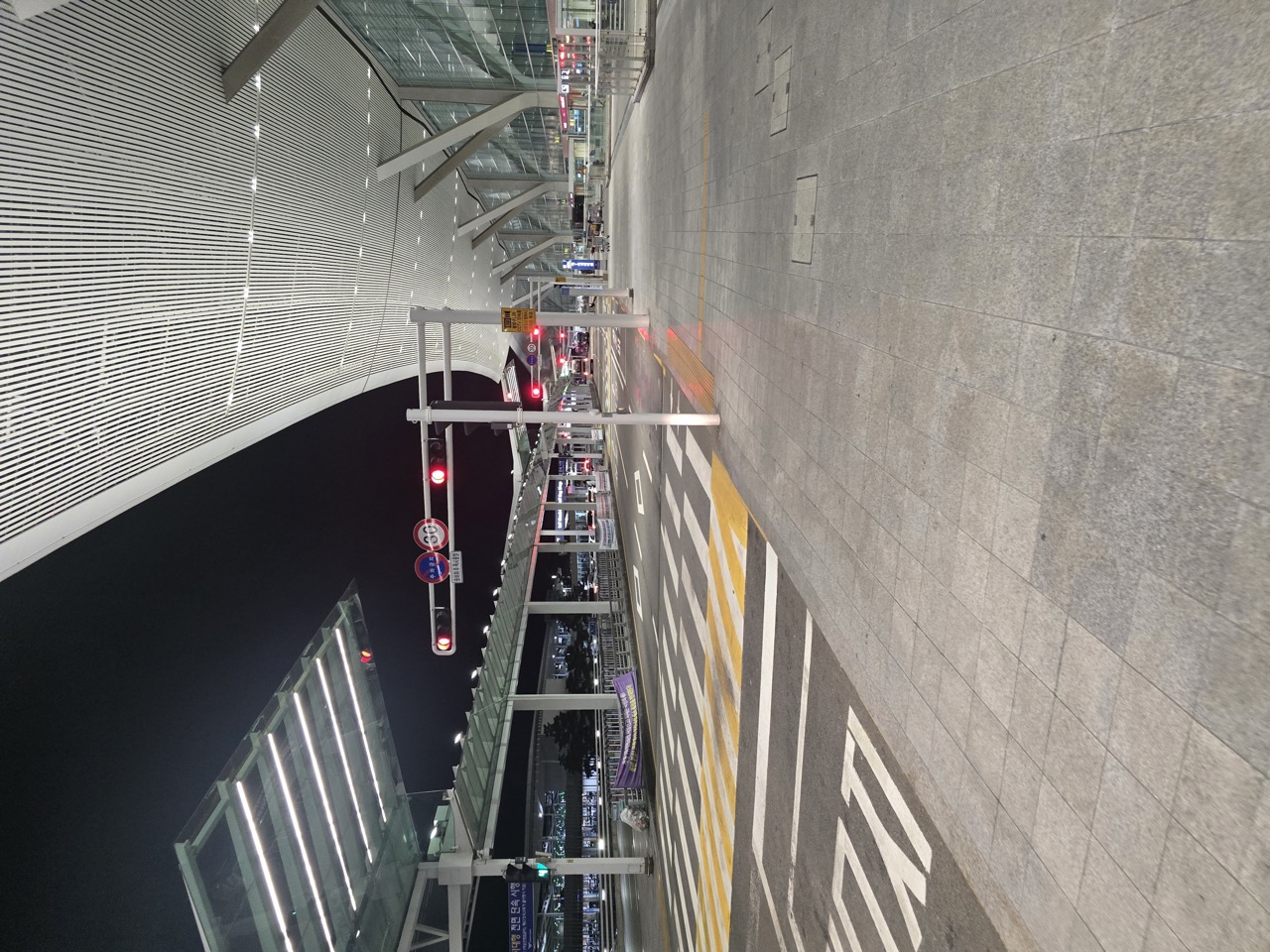 The glass facade and covered terminal access road at Incheon Airport Terminal 2 at night