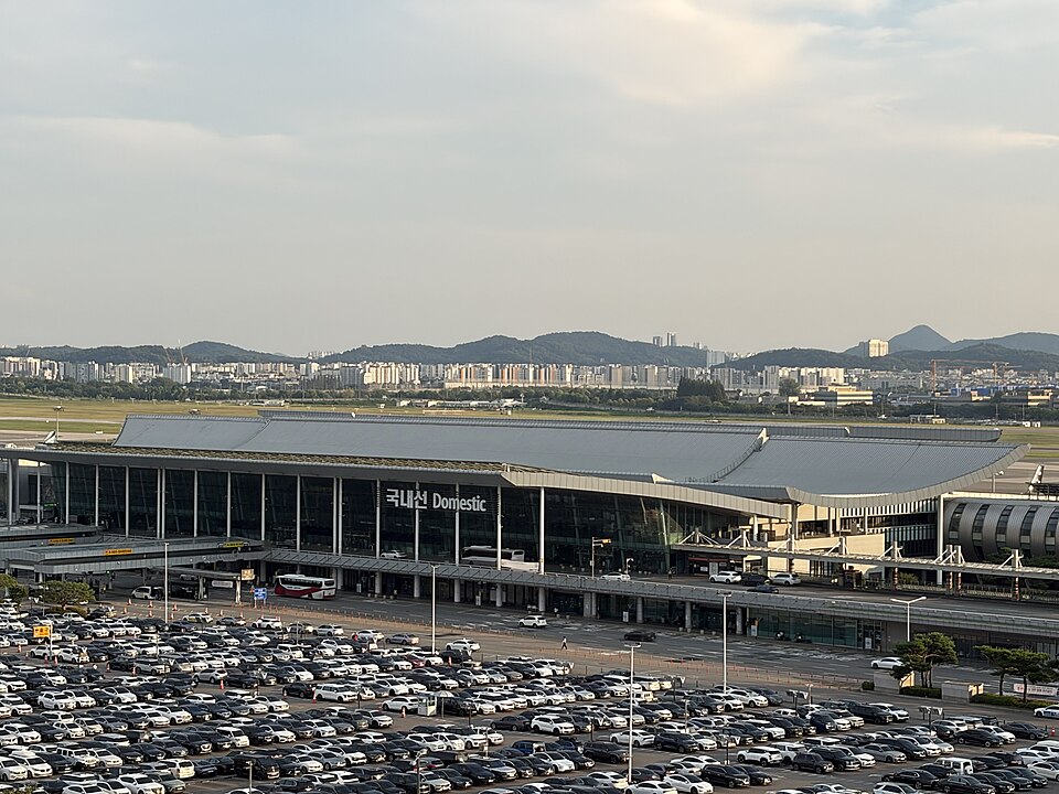 Gimpo Airport domestic terminal, with the Domestic sign above its glass facade and a car park in front.