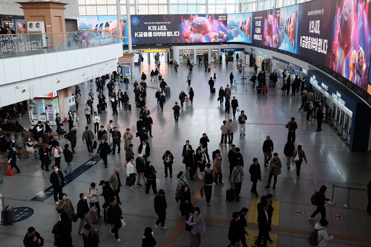 Passengers in the Seoul Station concourse, with ticket counters and departure access visible